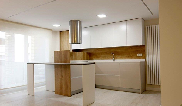 una cocina de discar con mueblesd e arriba blancos y los de abajo de madera de haya